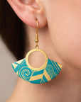 Gold and blue geometric earrings worn by a person