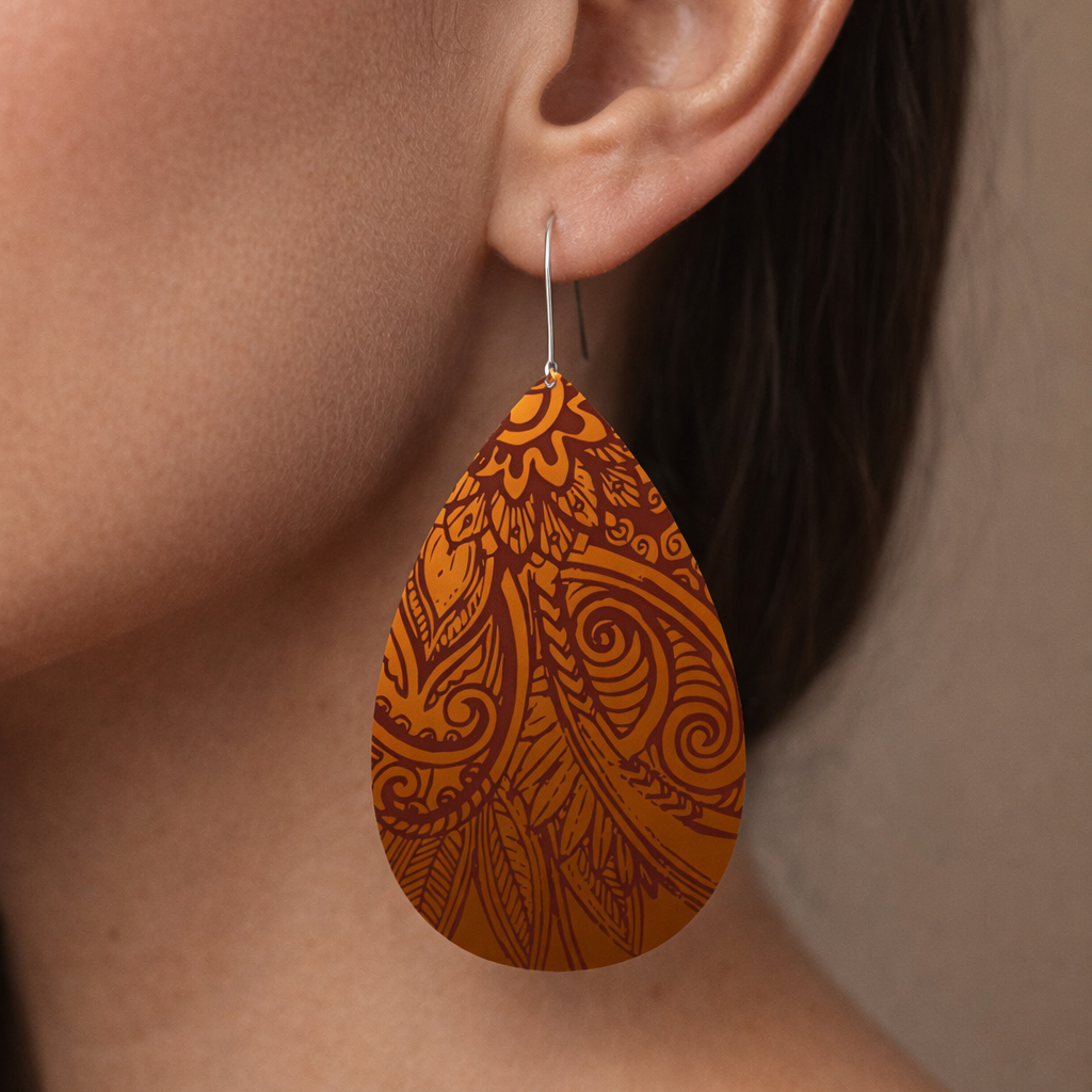 Teardrop-shaped earrings with intricate patterns worn by a person.