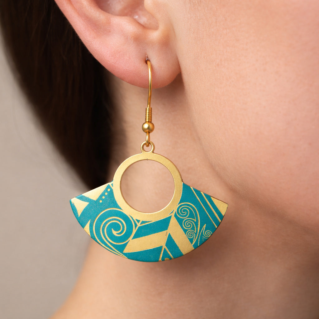 Gold and blue geometric earrings worn by a person